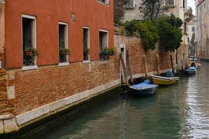 typisch eng Straßen und Kanäle zwischen bunt und schäbig Häuser im Venedig, Italien. historisch die Architektur im Venedig, geparkt Boote auf das Kanäle. foto