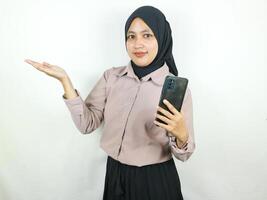 schön jung asiatisch Muslim Frau lächelnd zeigen Clever Telefon, Werbung Konzept foto