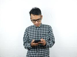 Porträt von asiatisch Mann halten Handy, Mobiltelefon Telefon Lektüre, Tippen Botschaft mit Fokus Gesicht Ausdruck. foto