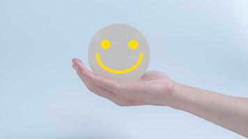 Kunde Bedienung Auswertung und Befriedigung Umfrage Konzepte. das Kunden Hand halten das glücklich Gesicht Lächeln Gesicht Symbol auf Kreis Holz foto