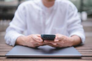 ein Geschäftsmann oder Freiberufler mit Computer Laptop und Smartphone Sitzung auf Tabelle draußen Arbeiten auf Geschäft oder Internet online Marketing foto