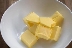 Butter Scheiben sind platziert auf ein Platte, Schnitt Butter in Würfel zum Backen Kuchen foto