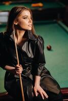 ein Mädchen mit ein Stichwort im ihr Hände sitzt auf ein Tabelle im ein Billard- Club.Russisch Billard foto