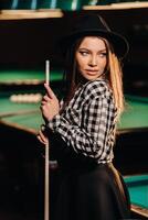 ein Mädchen im ein Hut im ein Billard- Verein mit ein Stichwort im ihr Hände.Billard Spiel foto