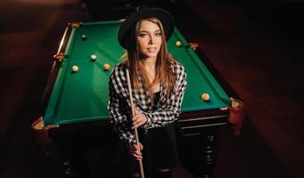 ein Mädchen im ein Hut im ein Billard- Verein mit ein Stichwort im ihr Hände.Billard Spiel foto