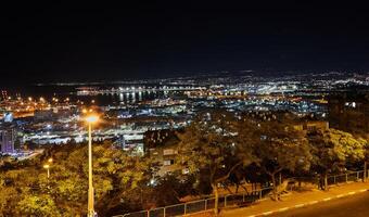 Erfahrung das zauberhaft Nacht Ambiente von Haifas geschäftig Hafen mit beleuchtet Straße Beleuchtung und das schimmernd Wasser von das Mittelmeer Meer, präsentieren das beschwingt Stadtbild im Israel. foto