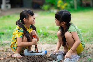 wenig Mädchen Pflanzen Pflanzen im Töpfe von recycelt Wasser Flaschen im das Hinterhof. recyceln Wasser Flasche Topf, Gartenarbeit Aktivitäten zum Kinder. Recycling von Plastik Abfall foto