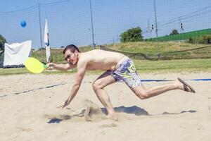 jung Erwachsene Mann Theaterstücke Tennis auf das Strand foto