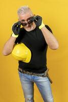 Arbeiter mit Helm und Handschuhe isoliert auf Gelb Hintergrund foto