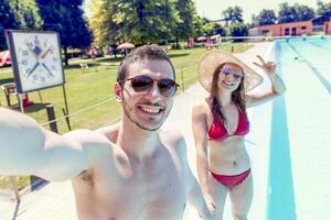 jung liebend Paar neben das Schwimmbad nimmt ein Selfie foto