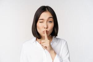 schließen oben Porträt von jung asiatisch Frau Herstellung Stille, shhh shush Zeichen, Drücken Sie Finger zu Lippen, nicht sprechen, behalten ruhig Geste, Weiß Hintergrund foto