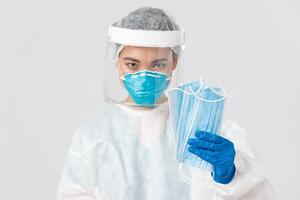 COVID-19, Coronavirus Krankheit, Gesundheitswesen Arbeitskräfte Konzept. zuversichtlich ernst aussehend weiblich asiatisch Arzt im persönlich schützend Ausrüstung darauf bestehen geduldig tragen medizinisch Masken, Weiß Hintergrund foto