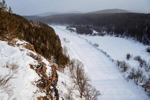 Winter Aussicht von das schneebedeckt Natur im das Berge. Ural Berge, Russland. Felsen Mauer auf ein gefroren Fluss. Süd- Ural, Tscheljabinsk Region foto