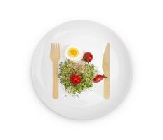Haufen von Alfalfa Sprossen auf Weiß Teller mit hölzern Gabel und Messer foto