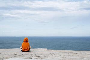 ein Mann sitzt im das rahmen, gegenüber das Meer. minimalistisch Schuss von Mann und das Meer. hell Kleidung, Ruhe Meer. Zeit allein. progulka durch das Meer foto