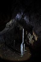 Höhle unter Tage. Eis Stalagmit im ein dunkel Höhle. tief unter Tage versteckt Schatz. Eis kalt dunkel Steine. Stille von Tiefe foto