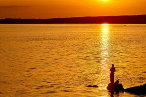 Fischer auf Seebrücke beim Sonnenuntergang Zeit. schön Sonnenuntergang im das Fluss und Mann mit Angeln Stangen foto