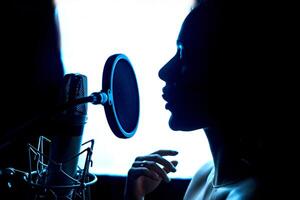 Silhouette von Musik- leidenschaftlich weiblich und das Mikrofon im das Fachmann Studio. Sänger im Vorderseite von ein Mikrofon. Nahansicht. foto