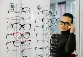 Stand mit Brille im ein Optiker Geschäft mit ein schön Mädchen im das Hintergrund. Brille Geschäft. Augenheilkunde. foto