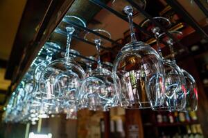 Reihen von sauber Weingläser hängen Über das Bar im das Cafe. Nahansicht foto