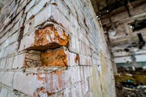 Nahansicht von alt Ziegel Mauer im das verlassen Ort. ruiniert und zusammengebrochen verlassen Gebäude mit gebrochen rot Ziegel foto