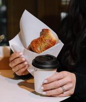 Mädchen Essen Croissant mit Pistazie Pulver und Trinken Kaffee auf Terrasse foto