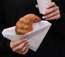 Mädchen Essen Croissant mit Pistazie Pulver und Trinken Kaffee auf Terrasse foto