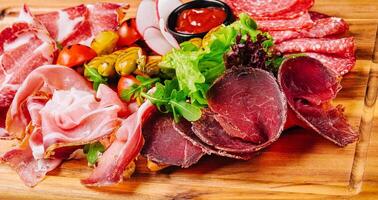 Vielfalt von Fleisch, Würste, Salami, Schinken, Oliven, gelegt aus auf ein hölzern Tafel foto