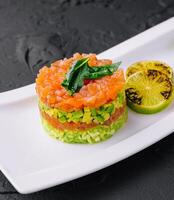 Lachs Tartar mit Avocado auf Teller foto