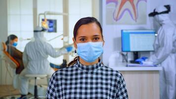 Porträt von Frau im Dental Büro suchen auf Kamera tragen Gesicht Maske Sitzung auf Stuhl im warten Zimmer Klinik während Arzt Arbeiten. Konzept von Neu normal Zahnarzt Besuch im Coronavirus Ausbruch. foto