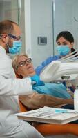 Zahnheilkunde Arzt tun hygienisch Reinigung von Zähne mit steril Dental Werkzeug. geduldig Lügen mit öffnen Mund im stomatologisch Büro, Stomatologe durchführen Untersuchung im modern Klinik. foto