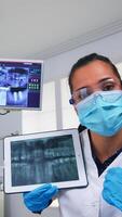 Zahnarzt zeigen auf Tablette Zähne Röntgen Überprüfung es mit geduldig. Arzt und Krankenschwester Arbeiten zusammen im modern stomatologisch Klinik, erklären zu alt Frau Radiographie von Zahn mit Notizbuch Anzeige foto