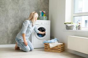 ein jung Hausfrau mit Waschen Maschine und Kleidung. Waschen Tag. foto