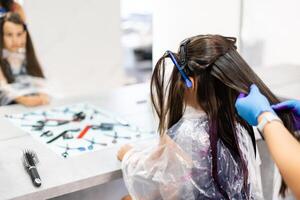 Friseur Farbstoffe Haar zum ein wenig Mädchen im ein Haar Salon. gefärbt, gebleicht Haar foto