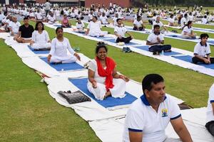 Neu Delhi, Indien, Juni 21, 2023 - - Gruppe Yoga Übung Session zum Menschen beim Yamuna Sport Komplex im Delhi auf International Yoga Tag, groß Gruppe von Erwachsene Teilnahme Yoga Klasse im Kricket Stadion foto