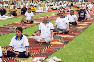 Neu Delhi, Indien, Juni 21, 2023 - - Gruppe Yoga Übung Session zum Menschen beim Yamuna Sport Komplex im Delhi auf International Yoga Tag, groß Gruppe von Erwachsene Teilnahme Yoga Klasse im Kricket Stadion foto