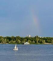 ein Segelboot im das Wasser mit ein Regenbogen im das Himmel foto