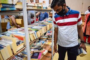 Delhi, Indien, Februar 17 2024 - - verschiedene Alter Gruppe Menschen lesen Vielfalt von Bücher auf Regal Innerhalb ein Bücherstand beim Delhi International Buch gerecht, Bücher im jährlich Buch Messe beim Bharat Mandapam Komplex foto