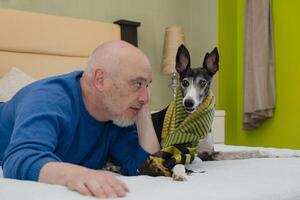 ein reifen Mann und seine Windhund Pose auf das Bett, foto