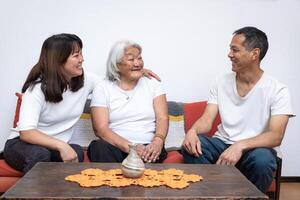 drei Menschen von ein Familie lächelnd und chatten Sitzung auf ein Sofa. foto