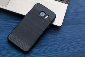 schwarzes Handy mit Kamera und Notebook auf Holztisch foto