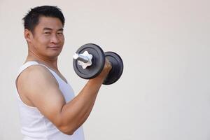 asiatisch Mann ist Heben Hantel zum Übung. Konzept, Übung zum Gesundheit Bodybuilding. stärken Muskel. Gewicht Heben. gesund Lebensstil. Arbeit aus machen stark von Körper. foto