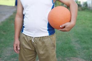 schließen oben Mann hält Orange Ball, draussen Hintergrund. Konzept, Sport Ausrüstung. abspielen Basketball zum Übung oder abspielen zum Wettbewerb. Übung zum Gesundheit. gesund Lebensstil. trainieren macht stark von Körper foto