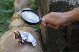 schließen oben Hand halt Vergrößerung Glas zu machen Feuer zum Verbrennung Papier. Konzept, Wissenschaft Experiment Über konvex Linse, halt Vergrößerung Glas zwischen das Sonne und Tinder. praktisch Überleben Fähigkeiten. foto