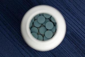 blaue Tabletten Pillen Grippe Arzt antibiotische Pharmazie Medizin Medizin in einer Flasche auf blauem Holz Hintergrund