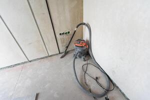 industriell Vakuum Reiniger auf das staubig Fußboden von Konstruktion Seite? ˅. foto