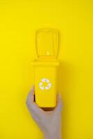 Hand halten Gelb Container mit recycelbar Deckel. foto