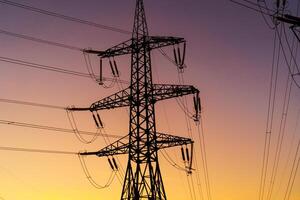 Energie Verteilung Netzwerk - - Elektrizität Pylone gegen Orange und Gelb Sonnenuntergang. Nahansicht foto