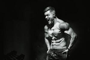 brutal stark sportlich Männer Pumpen oben Muskeln. trainieren und Bodybuilding Konzept. schwarz und Blau Licht Hintergrund. gut aussehend Mann mit nackt Torso. Fitness Modell- ist posieren. foto