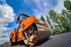 Straße Reparatur, Verdichter liegt Asphalt. schwer Besondere Maschinen. Asphalt Fertiger im Betrieb. Seite Sicht. Nahaufnahme. foto